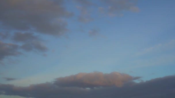 Commerciële passagiersvliegtuig vliegt overhead, blauwe hemel, wit blauw paars wolken — Stockvideo