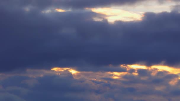 Golden sun breaking through dark blue fluffy quickly passing clouds 4K Timelapse — Stock Video