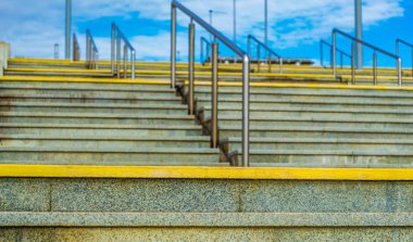 Cennete giden modern granit merdivenler. Arka planda, mavi gökyüzü ve beyaz bulutlar. Çelik korkuluklar. Berrak, güneşli hava.