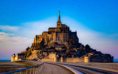 Mont Saint Michel, Fransa güzel ortaçağ kalesi. Adada bulunan manastır, surlarla çevrilidir. Köprü adaya gidiyor. Güzel mavi gökyüzü ve kabarık beyaz bulutlar. Gündüz