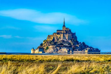 Mont Saint Michel şaşırtıcı güzel ortaçağ kalesi. Manastır, adada bulunan, surlar ile çevrili. Her taraftan denizle yıkanır. Güzel mavi gökyüzü ve kabarık beyaz bulutlar