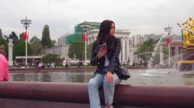 Bir parkta yürürken bir cep telefonu kullanarak çekici bir kadın. Ultra Hd görüntü
