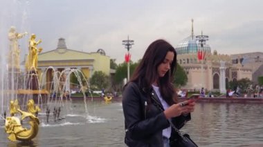 Çekici, şık kız, siyah ceket, gülümseyen ve bir cep telefonu kullanarak