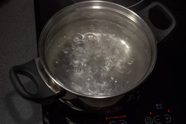 Boiling water in pan on electric stove in the kitchen — Stock Photo, Image