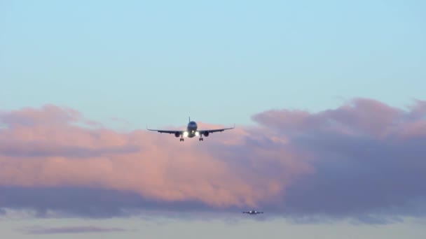 Dos aviones están volando en el cielo. En el cielo azul de fondo, nubes naranja púrpura — Vídeo de stock