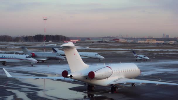 Cinq petits et moyens avions d'affaires stationnés à l'aéroport. Neige hivernale. 4K — Video