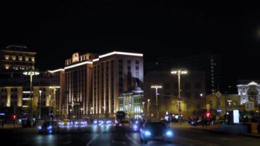 Gece şehir manzarası. Arabalar köşeyi dönünce. Yayalar yolun karşısına geçiyor. 4k