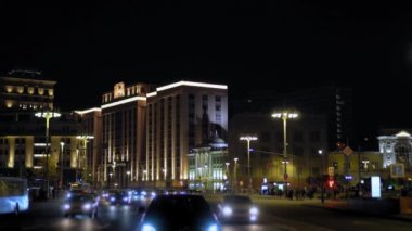 Gece şehir manzarası. Arabalar köşeyi dönünce. Yayalar yolun karşısına geçiyor. 4k