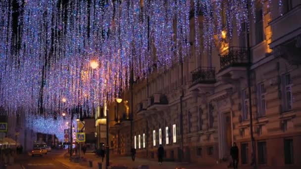 Gatan i natt staden dekorerad med lila ljus. Fasader av byggnader. 4K — Stockvideo