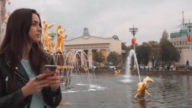 Çekici şık kız çeşme arka planda cep telefonu mesaj yazıyor