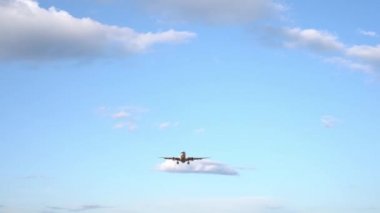 Modern büyük uçak mavi gökyüzünde uçuyor. Arka planda beyaz bulutlar var. 4k