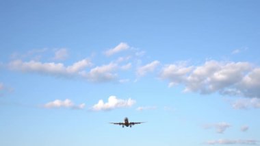 Modern büyük uçak mavi gökyüzünde uçuyor. Arka planda beyaz bulutlar var. 4k