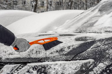 Arabadaki karı temizlemek için fırça kullanan adam