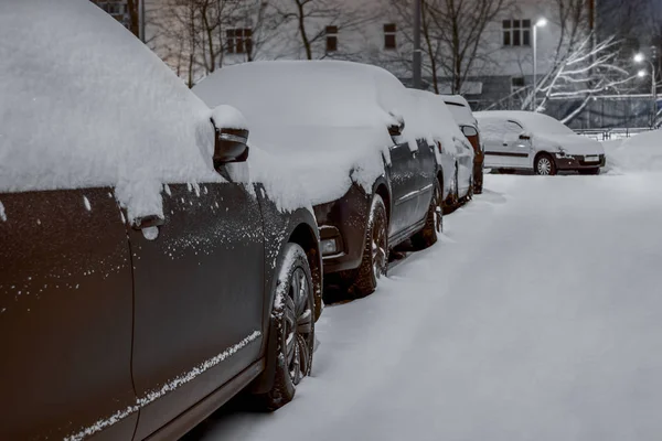 Bilar och vägen är täckta med lager snö. byggnad i th — Stockfoto