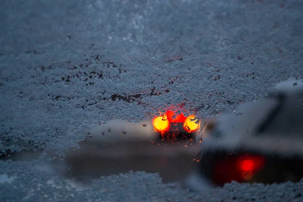 Ветровое стекло в снегу, огни от машин на заднем плане. Вид — стоковое фото