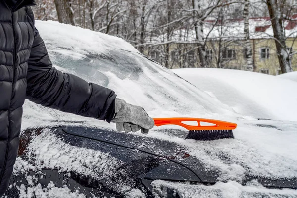 Uomo utilizzando spazzola per rimuovere la neve dalla macchina — Foto Stock