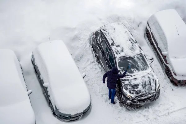 Os homens, com pincel, removem a neve do carro. Vista superior, fote aéreo — Fotografia de Stock