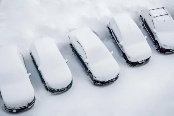 Carros e a estrada estão cobertos com uma camada de neve. construção em — Fotografia de Stock