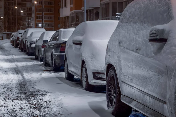 Carros e a estrada estão cobertos com uma camada de neve. construção em — Fotografia de Stock