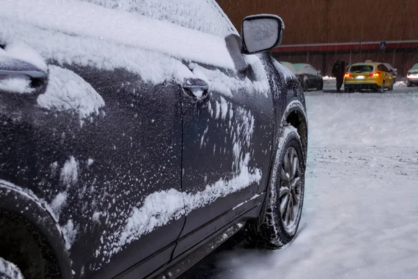 Bilen är täckt av lager av snö. Staden � � � � � ljus och snöstorm i Royaltyfria Stockbilder