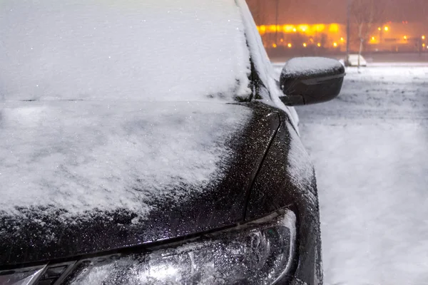 Bilen är täckt av lager av snö. Staden � � � � � ljus och snöstorm i Stockbild