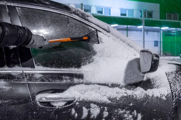 Man använder borste för att ta bort snö från bilen Stockbild