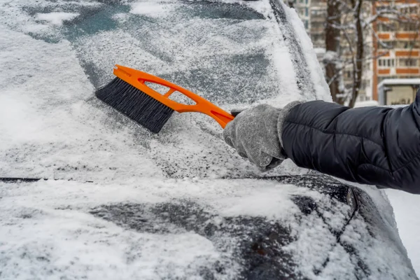 Man använder borste för att ta bort snö från bilen Stockfoto
