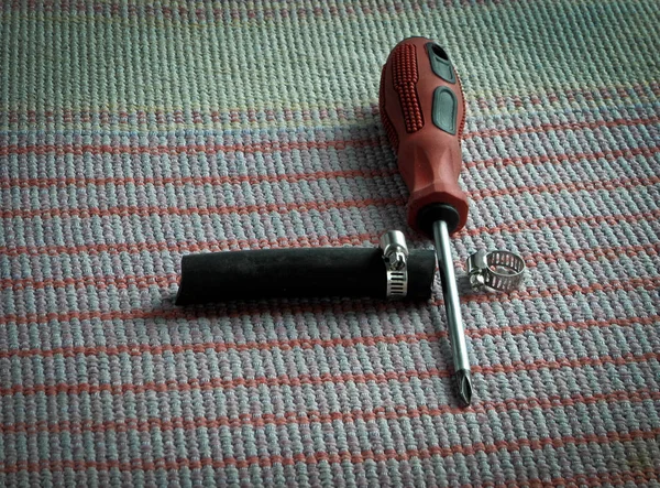 Cacciavite per utensili, morsetti e tubo di gomma sul tavolo . — Foto Stock