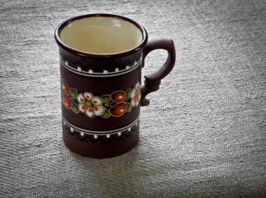 Kahverengi kil Kupası emayeler tablo üzerinde gri bir masa örtüsü ile.