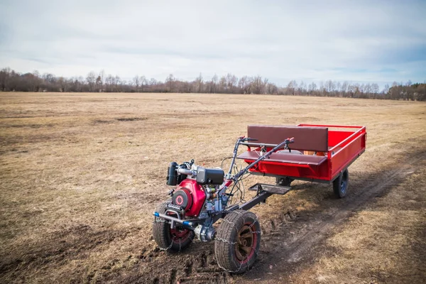 Motoblock com um reboque indo em uma estrada de campo na primavera em março, a nova temporada de trabalho de campo — Fotografia de Stock