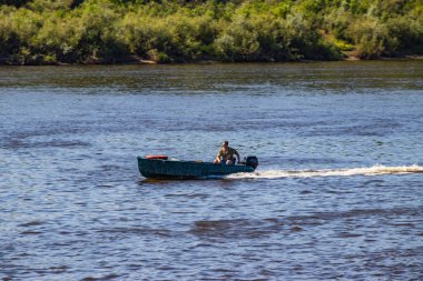Anglers güneşli bir yaz gününde balık arayan bir nehir üzerinde motorboat gitmek