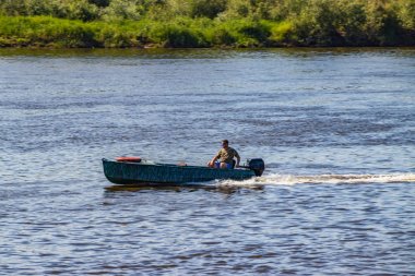 Anglers güneşli bir yaz gününde balık arayan bir nehir üzerinde motorboat gitmek