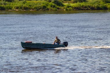 Anglers güneşli bir yaz gününde balık arayan bir nehir üzerinde motorboat gitmek