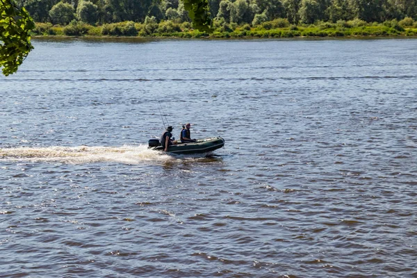 Рыбаки плывут на моторной лодке по реке в поисках рыбы в солнечный летний день — стоковое фото