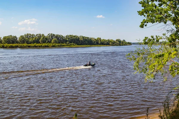 Sportfiskare gå motorbåt på en flod som söker fisk på en solig sommardag — Stockfoto