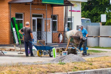 İnşaatçılar Beton mikser ile somut bir çözüm yoğurma.