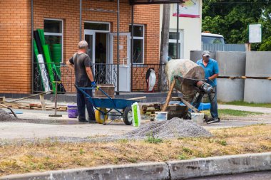 İnşaatçılar Beton mikser ile somut bir çözüm yoğurma.