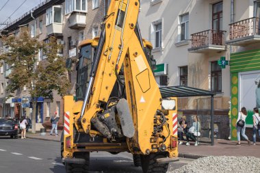 Tekerlekli turuncu ekskavatör şehirde çalışıyor