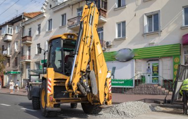 Tekerlekli turuncu ekskavatör şehirde çalışıyor