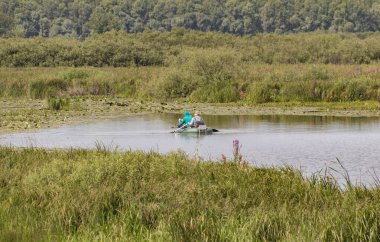 Teknedeki balıkçılar gölette yüzüyor