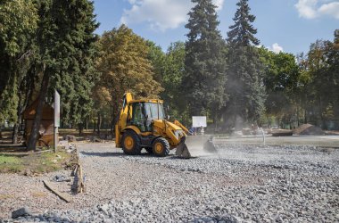Tekerlekli turuncu ekskavatör şehirde çalışıyor