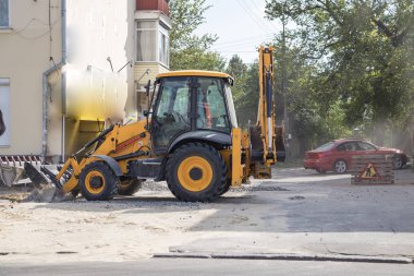 Tekerlekli turuncu ekskavatör şehirde çalışıyor