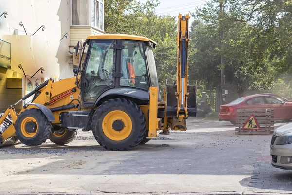 Tekerlekli turuncu ekskavatör şehirde çalışıyor