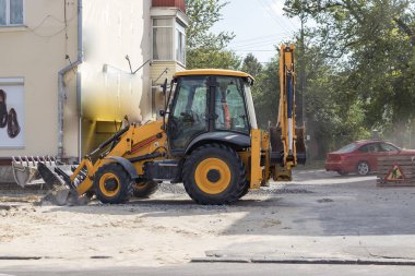 Tekerlekli turuncu ekskavatör şehirde çalışıyor