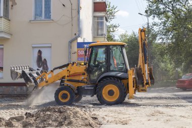 Tekerlekli turuncu ekskavatör şehirde çalışıyor