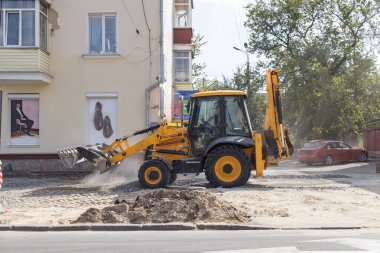 Tekerlekli turuncu ekskavatör şehirde çalışıyor
