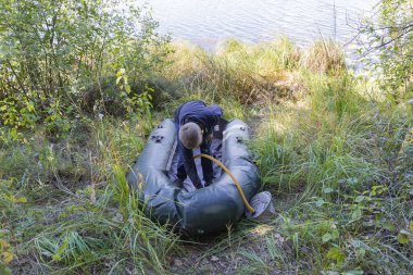 Bir çocuk şişme bir tekne hazırlıyor.