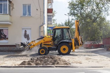 Tekerlekli turuncu ekskavatör şehirde çalışıyor