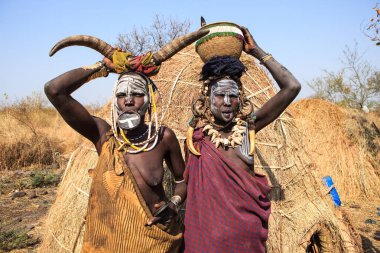 Jinka, Omo Nehri Vadisi, Etiyopya - Ocak, 2018. Bir sepet başlarına tutan iki Mursi kabile kadın bir geleneksel dudak plaka