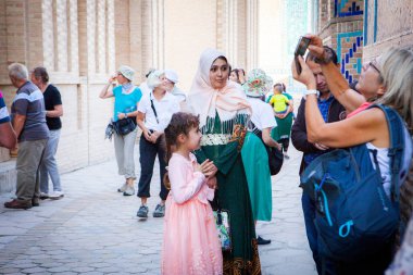 Semerkand, Özbekistan - Ekim, 2016: Turistler ve yerliler için Shohizinda ensemble keşfetmek. Avrupa Bayan resimler, yerel kadın ve kızı birisi için poz alarak